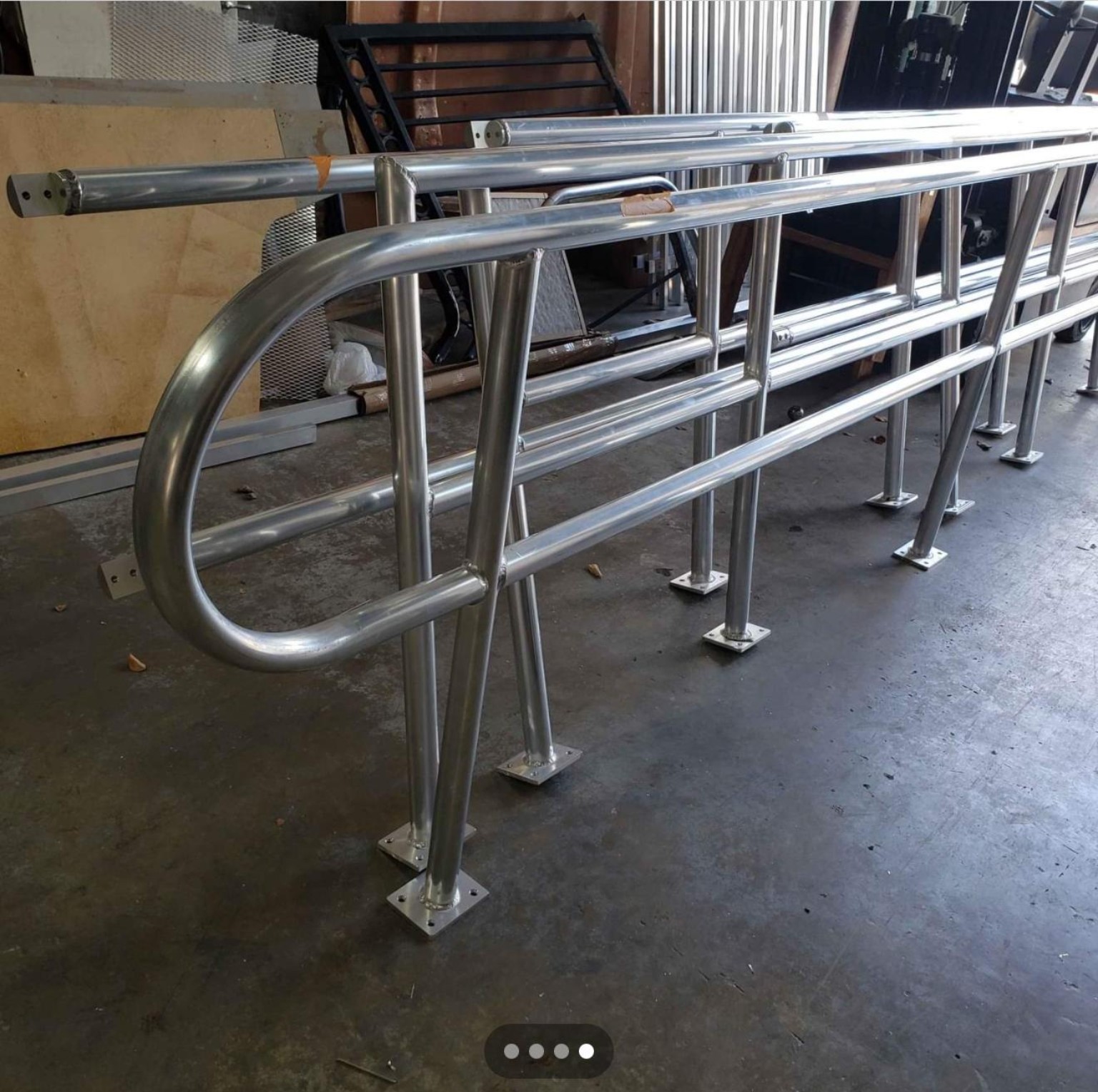 Custom curved metal railings with welded horizontal bars and base plates in the workshop