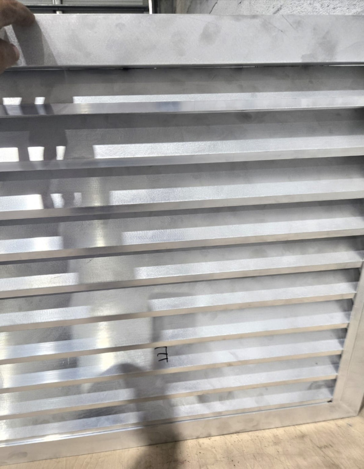 Unfinished silver metal panel with horizontal bars during fabrication